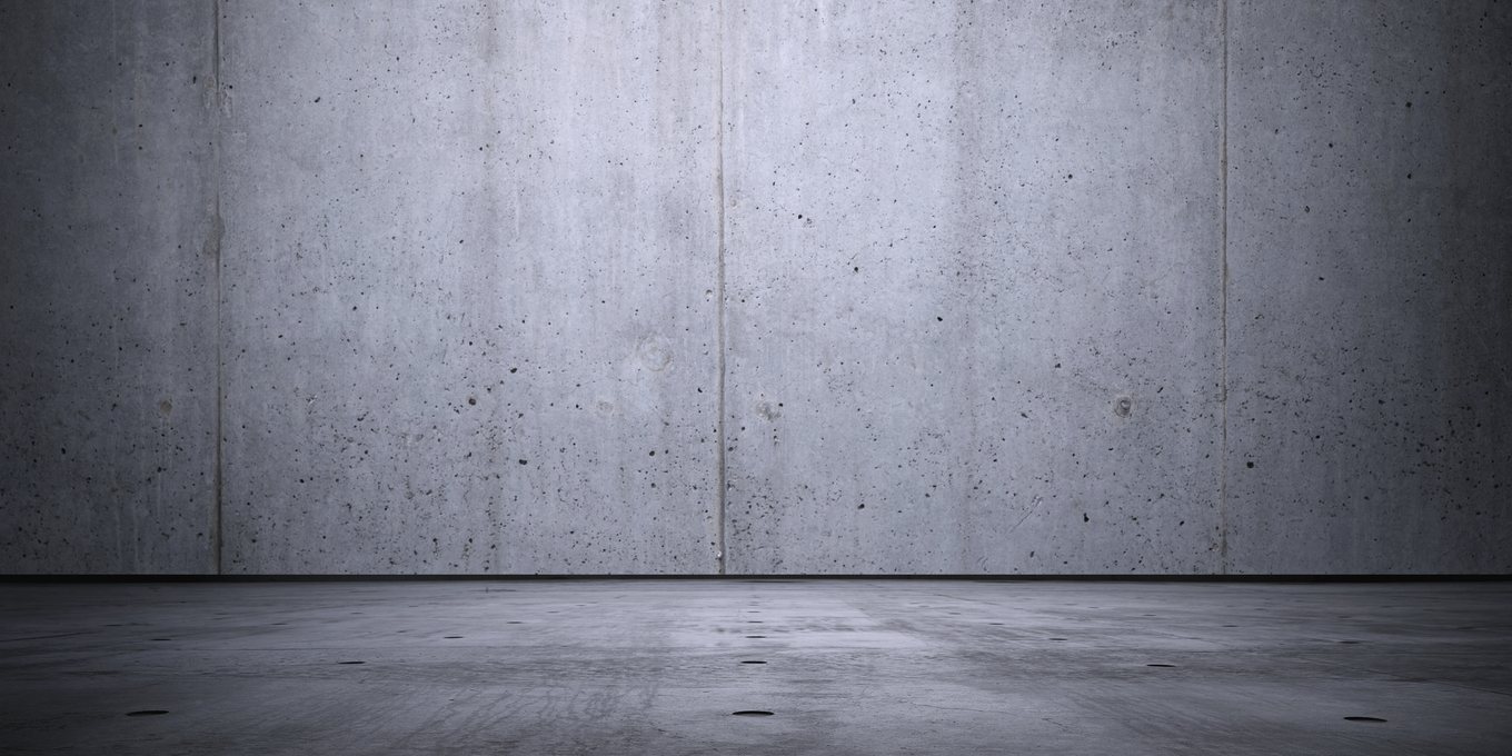 A worn plaster wall meeting a concrete floor
